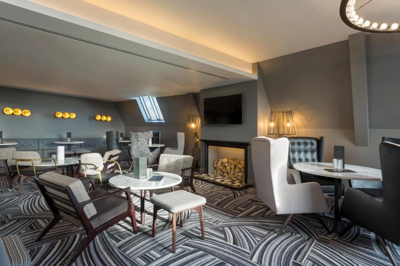 Hotel lobby lounge with tables, chairs and a fireplace at Hotel Indigo Cardiff